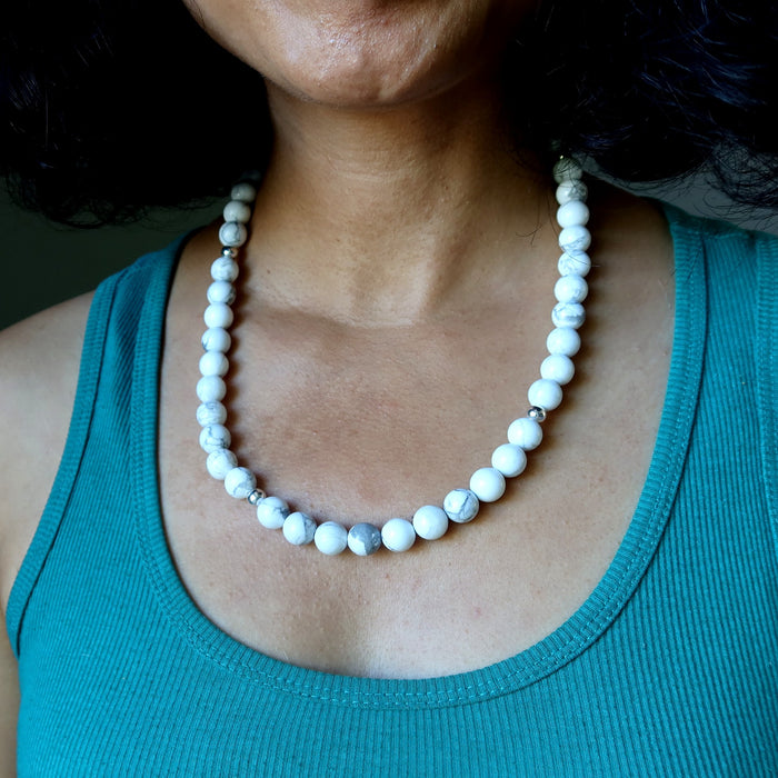 Person wearing a white beaded Howlite necklace with a teal top
