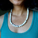Person wearing a white beaded Howlite necklace with a teal top