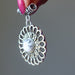 Silver Howlite pendant held by a hand against a gray background