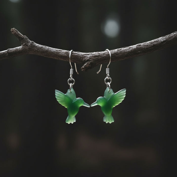 Green jade bird-shaped earrings on a wooden surface