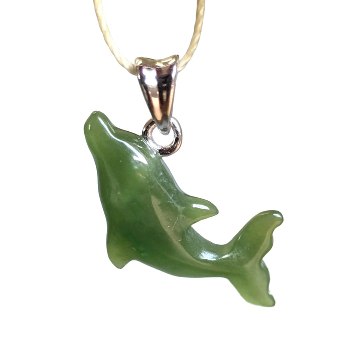 Green dolphin pendant on a gold chain against a blurred background