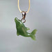 Green dolphin pendant on a gold chain against a gray background