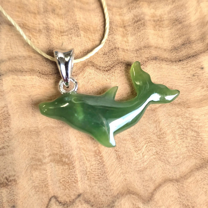 Green dolphin pendant on a necklace against a wooden background