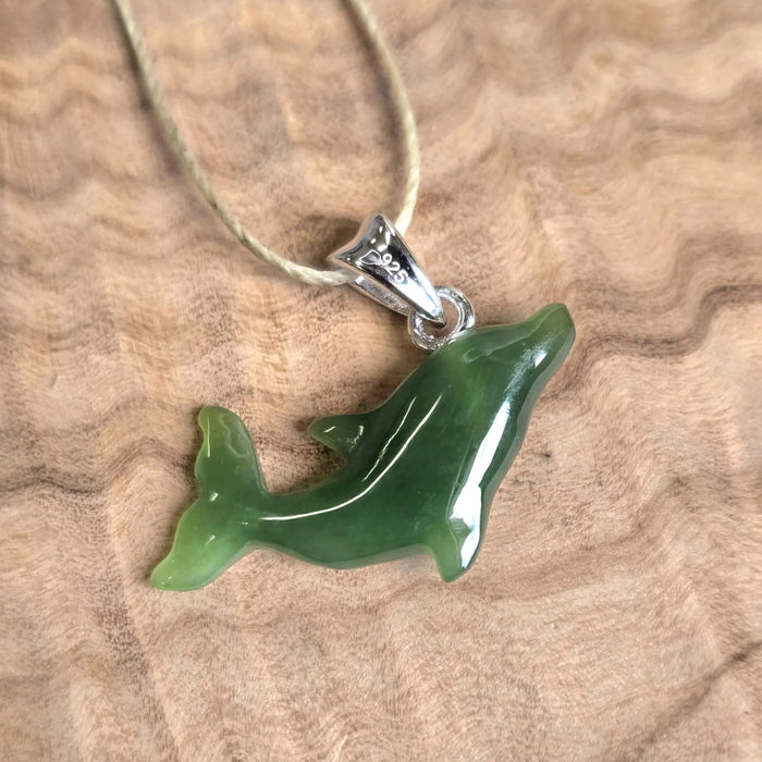 Green dolphin pendant on a beige background