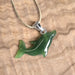 Green dolphin pendant on a beige background