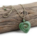 Green jade pendant on a rope against a white background