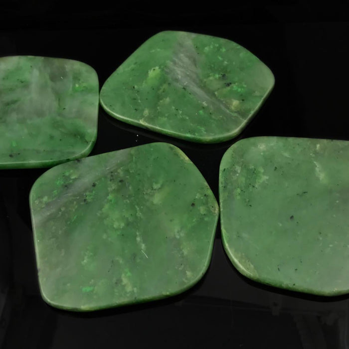 Four green stone jade slabs on a black background
