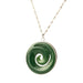 Green jade spiral pendant necklace on a wooden surface