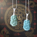 Two jade pendants on silver chains against a decorative background with Chinese characters.