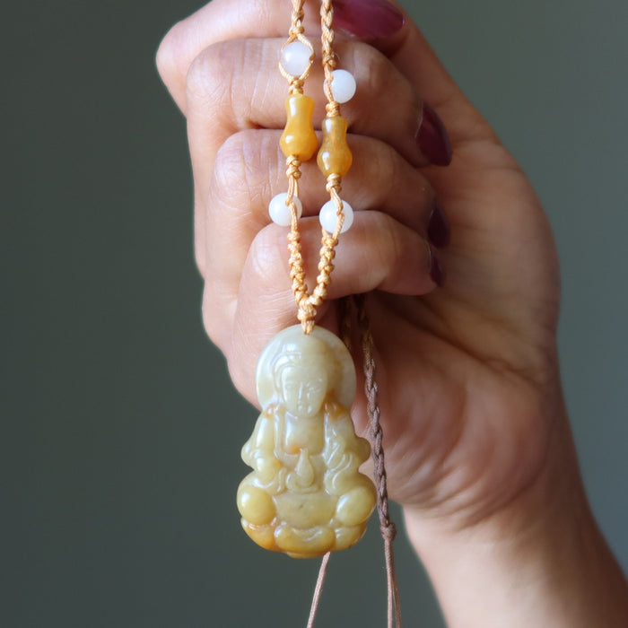 Hand holding a jade necklace with beads against a neutral background