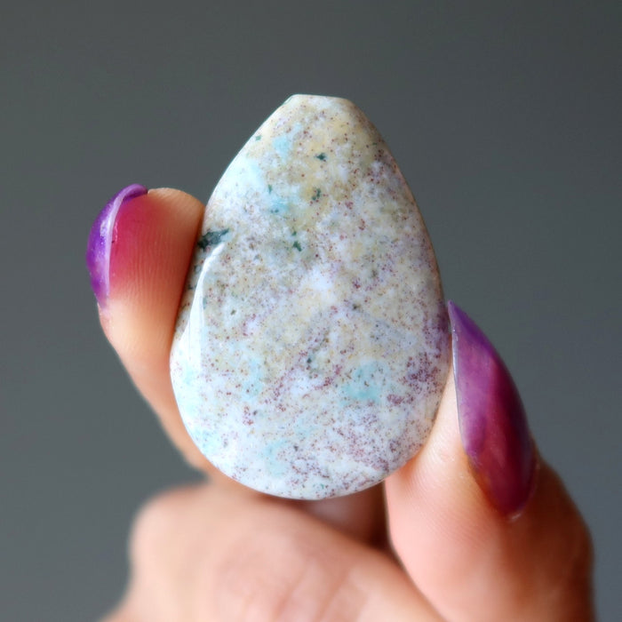 Hand holding a textured stone against a gray background