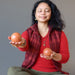 Woman holding two red jasper spheres against a gray background