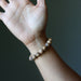 Hand wearing a beaded Landscape Jasper bracelet against a dark background