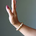 Hand wearing a beaded Landscape Jasper bracelet against a plain background