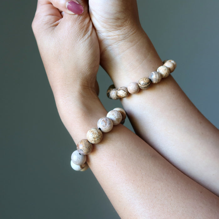 Two wrists wearing beaded Landscape Jasper bracelets against a neutral background