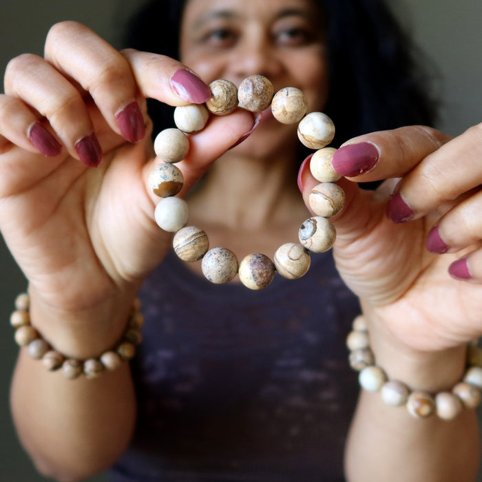Person holding a beaded Landscape Jasper bracelet with a neutral background