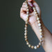 Hand holding a beaded Landscape Jasper necklace against a dark background