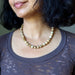 Close-up of a person wearing a Landscape Jasper necklace  with a neutral background