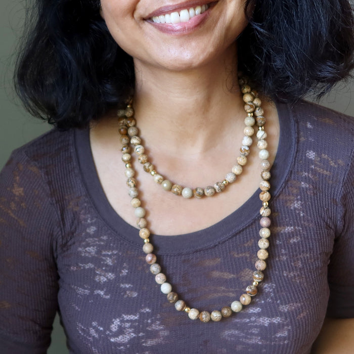Woman wearing a long beaded Landscape Jasper necklace with a blurred background
