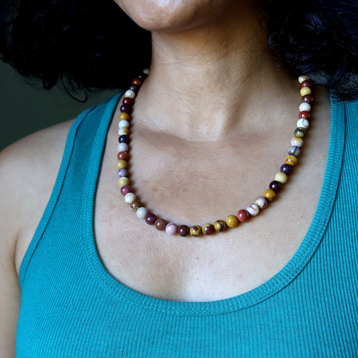 Person wearing a colorful mookaite jasper beaded necklace with a teal tank top