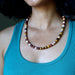 Person wearing a colorful mookaite jasper beaded necklace with a teal tank top