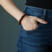 Person wearing blue jeans with a hand in the pocket, wearing a jasper bracelet