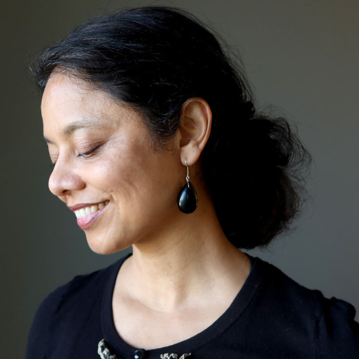 Woman wearing black Jet earrings against a neutral background