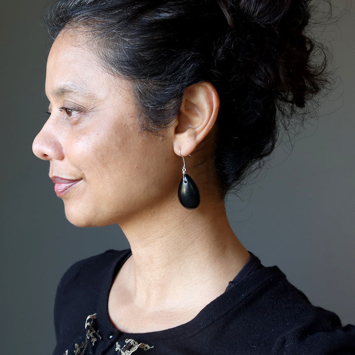 Woman wearing a black Jet earring against a neutral background