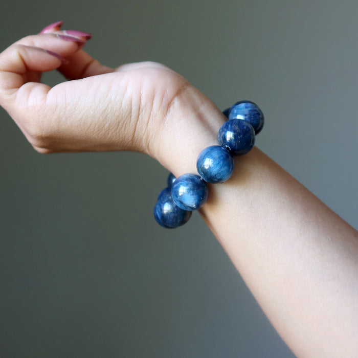 Blue beaded kyanite bracelet on a wrist against a neutral background