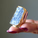 Hand holding a Kyanite with gold accents against a neutral background