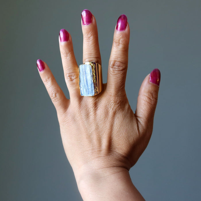 Hand with a gold and blue Kyanite  ring on a gray background
