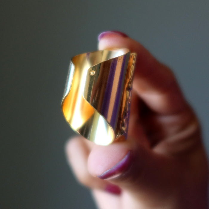 Kyanite Gold ring held by a hand with purple nail polish against a dark background
