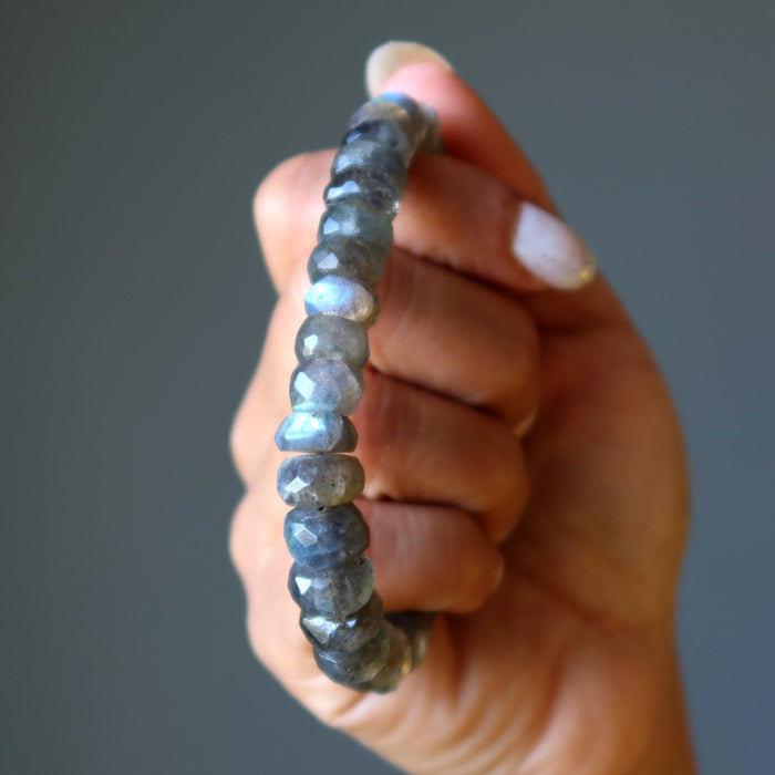 Hand holding a beaded Labradorite bracelet against a neutral background