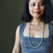 Woman wearing a blue patterned dress with a long Labradorite necklace against a dark background