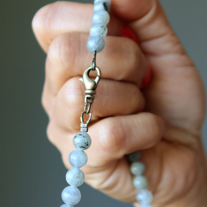 Hand holding a beaded Labradorite necklace with a blurred background