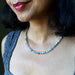 Close-up of a woman wearing a beaded Labradorite necklace with a blurred background