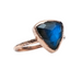 Ring with a blue gemstone and rose gold setting on a white background