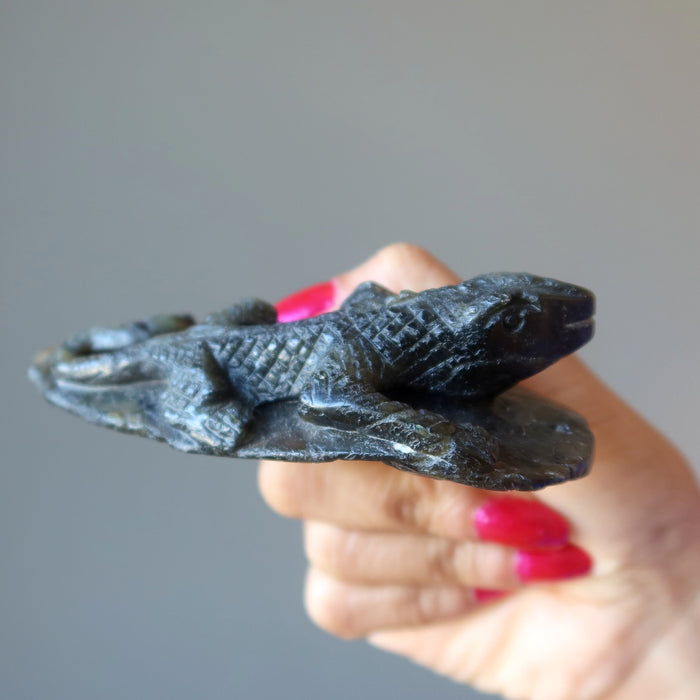 hand holding up a labradorite lizard carving
