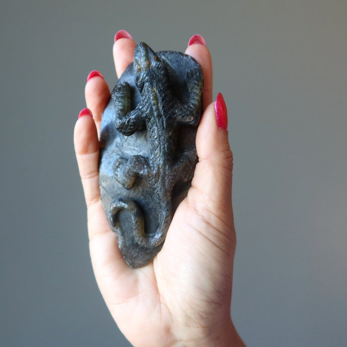 hand holding up a labradorite lizard carving