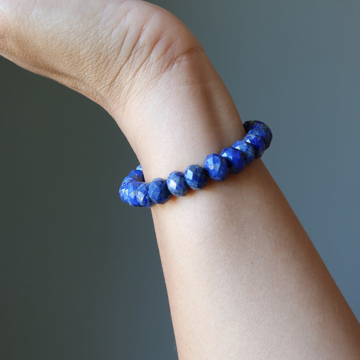 Blue beaded Lapis bracelet on a wrist against a gray background