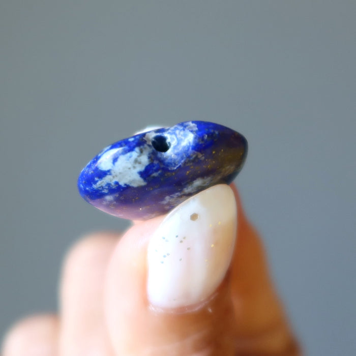 Blue and white stone held between fingers against a gray background