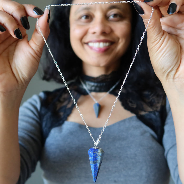 Person holding a lapis silver necklace with a blue pendant