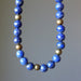 Lapis Lazuli necklace with blue and gold beads on a gray background