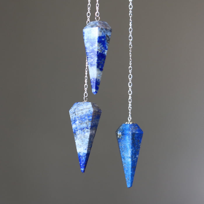 Blue crystal lapis pendulums on silver chains against a gray background