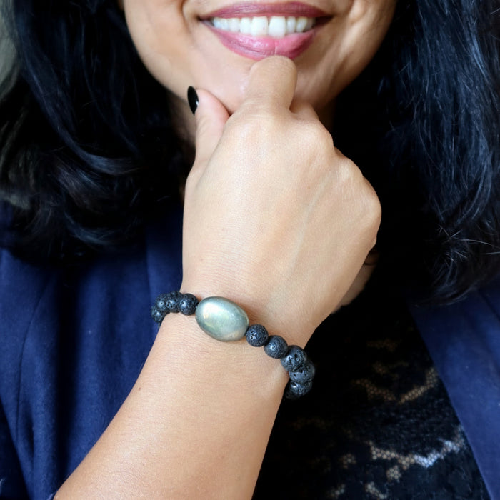 Person wearing a bracelet with lava and pyrite on a dark background