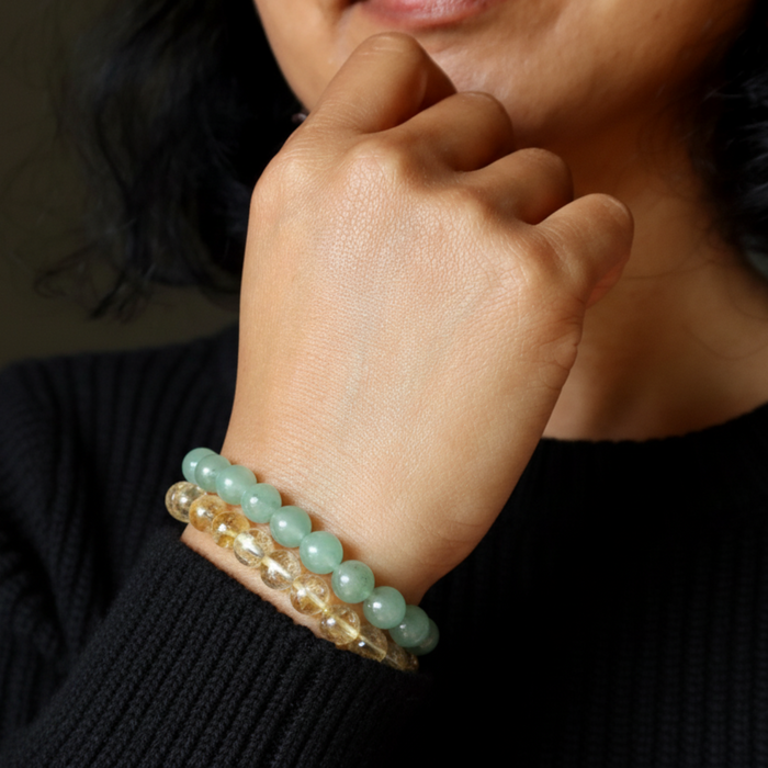 Close-up of a hand wearing two beaded bracelets on a blurred background