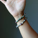 Hand wearing two beaded bracelets on a dark background