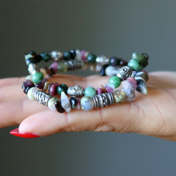 Stack of colorful beaded bracelets on a hand against a neutral background