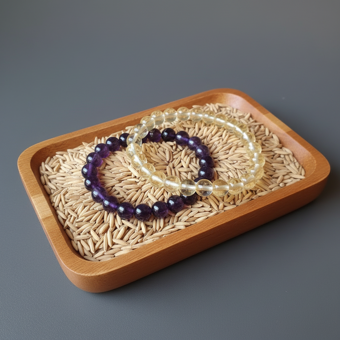 Two beaded bracelets on a wooden tray with a gray background