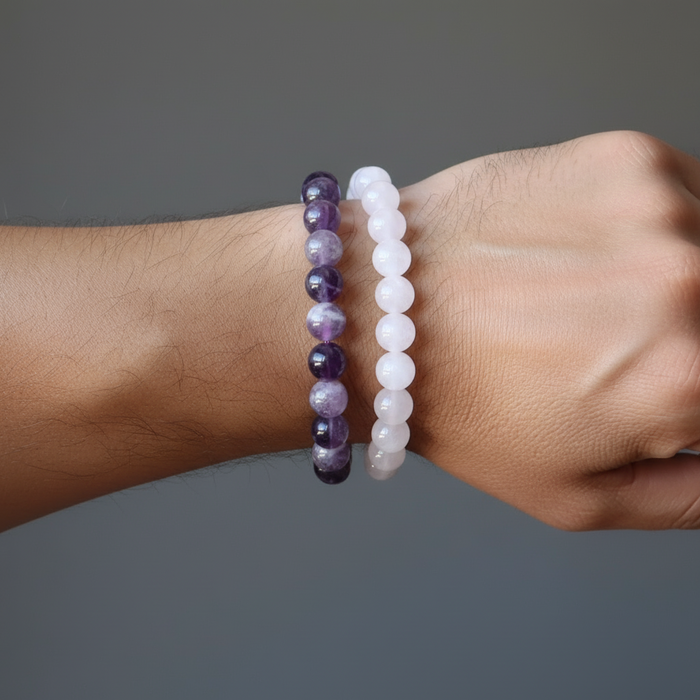 Two beaded bracelets on a wrist against a gray background